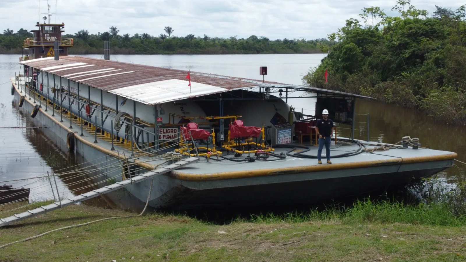 Barcaza cisterna de Amazon Gas amarrada en el embarcadero de la planta, con un operario sobre cubierta